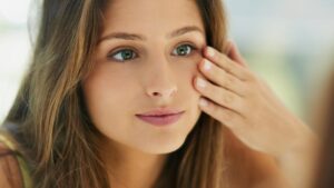 Mujer joven con piel saludable aplicando cuidados faciales en casa, ideal para ilustrar consejos de dermatología estética de Airklinic Valencia.